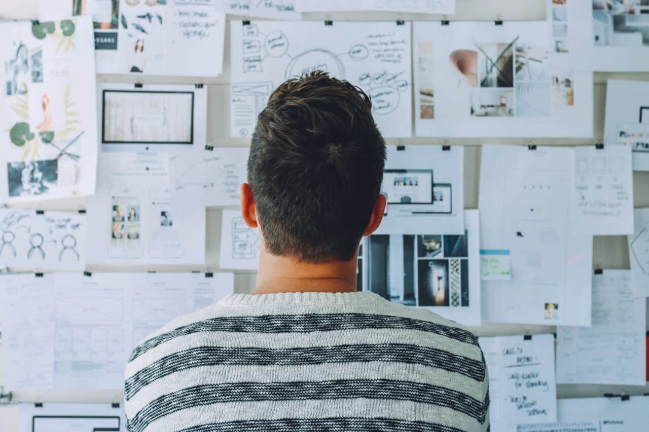 a person looking at the wall full of business ideas scribbles